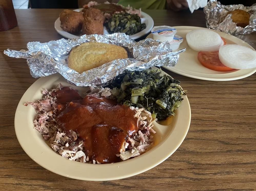 BBQ pork plate with greens, baked potato in foil and sliced onion and tomato