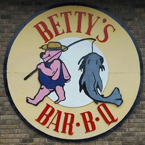 Betty's Bar-B-Q circular logo with a pig carrying a catfish