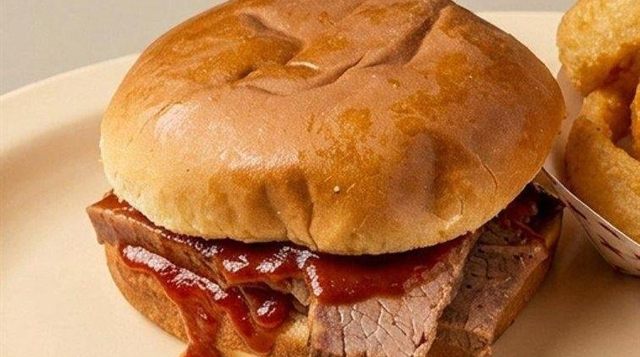 BBQ brisket sandwich with barbecue sauce and onion rings at Betty's Bar-B-Q in Anniston, AL