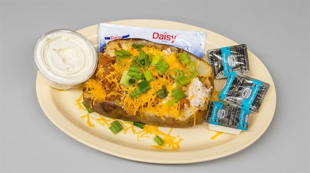 Stuffed baked potato loaded with cheese and chives, with sour cream on the side, at Betty's Bar-B-Q in Anniston, AL
